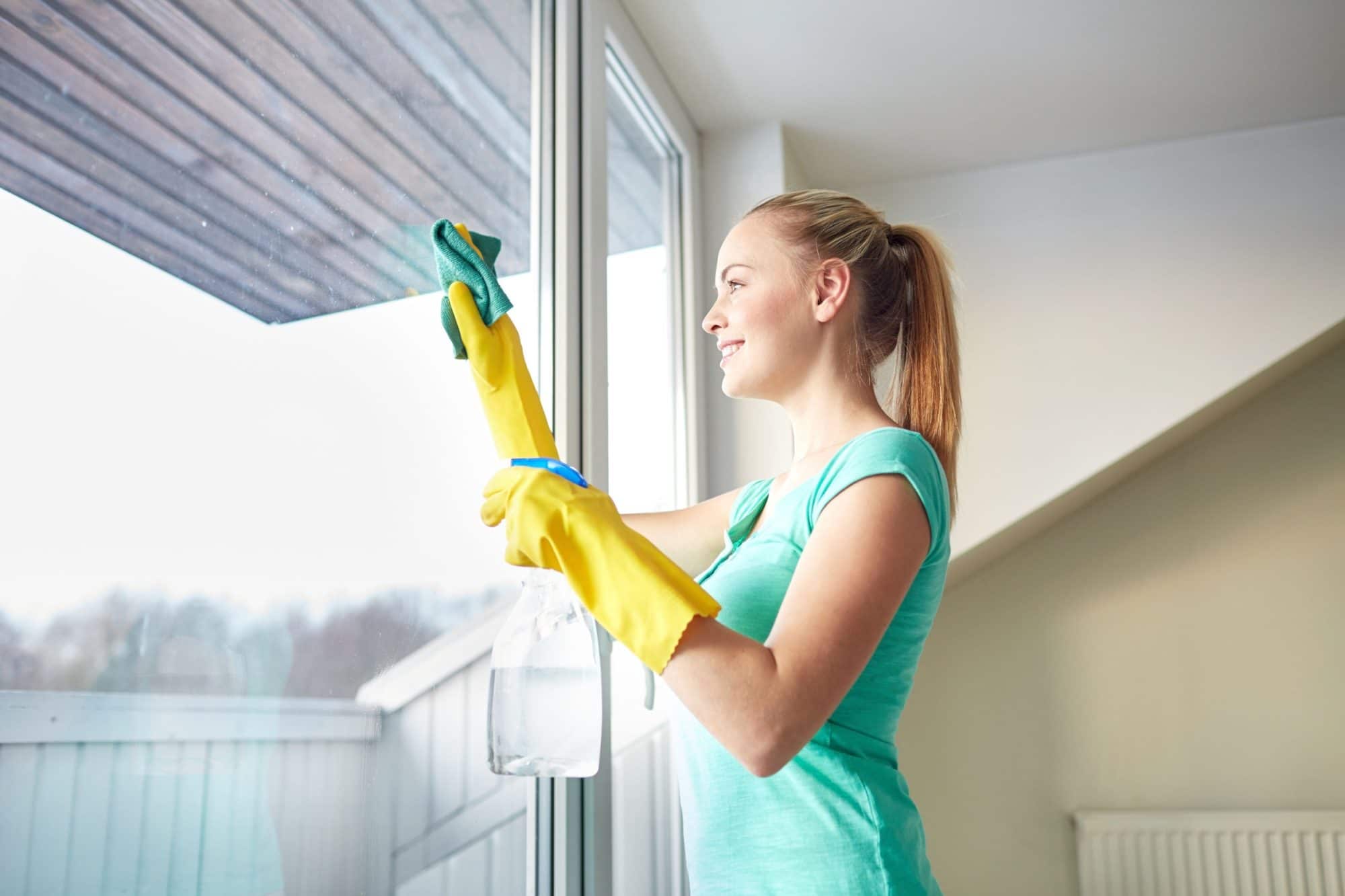 Femme nettoyant des vitres / happy woman in gloves cleaning window with rag